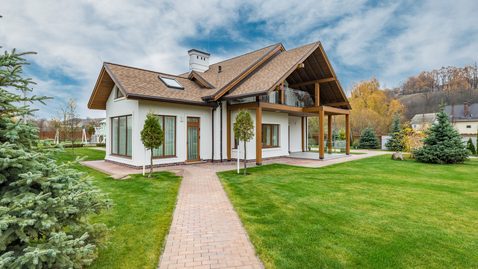 Einfamilienhaus mit sauber gepflastertem Gartenweg und Rasenflächen