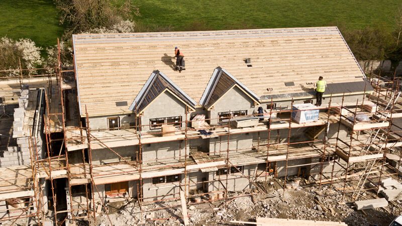 Eingerüsteter Neubau: frisches Mauerwerk und Dachstuhl aus der Vogelperspektive