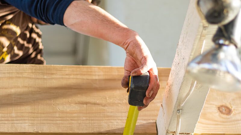 Handwerker nimmt Maß an einer Holzkonstruktion im Innenausbau